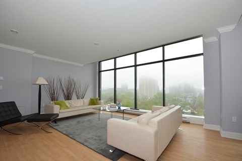 A modern living room with a large window overlooking a foggy cityscape.