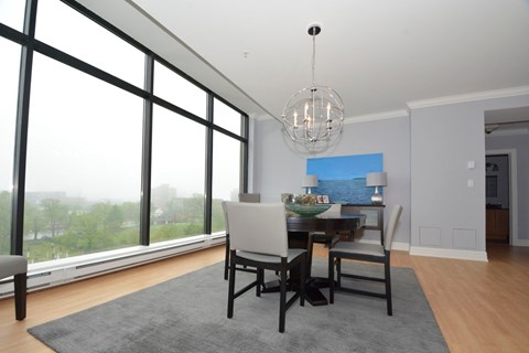 A dining room with a table and chairs and a view of the outside.