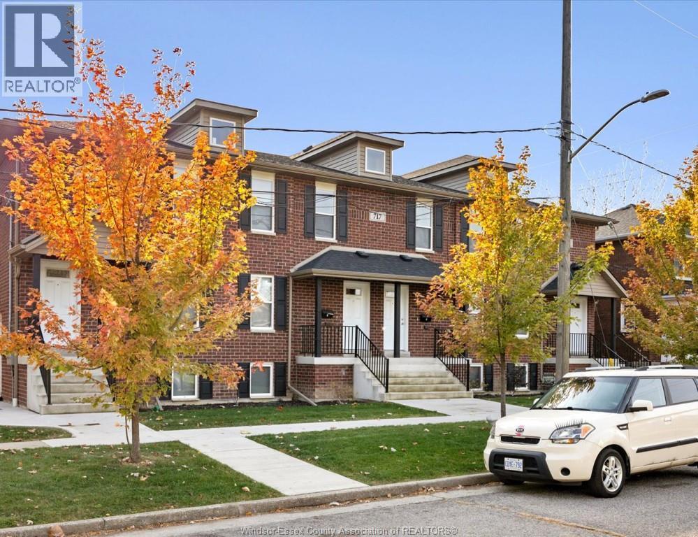 A white car is parked in front of a brick house.