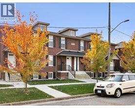 A white car is parked in front of a brick house.