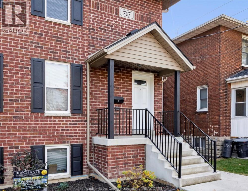 A red brick house with a white door and black railings.