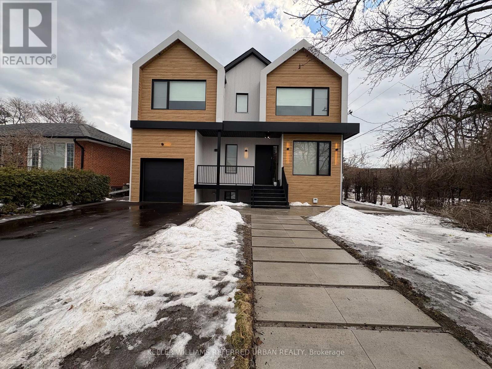 A modern two-story house with a black front door and a snow-covered sidewalk.