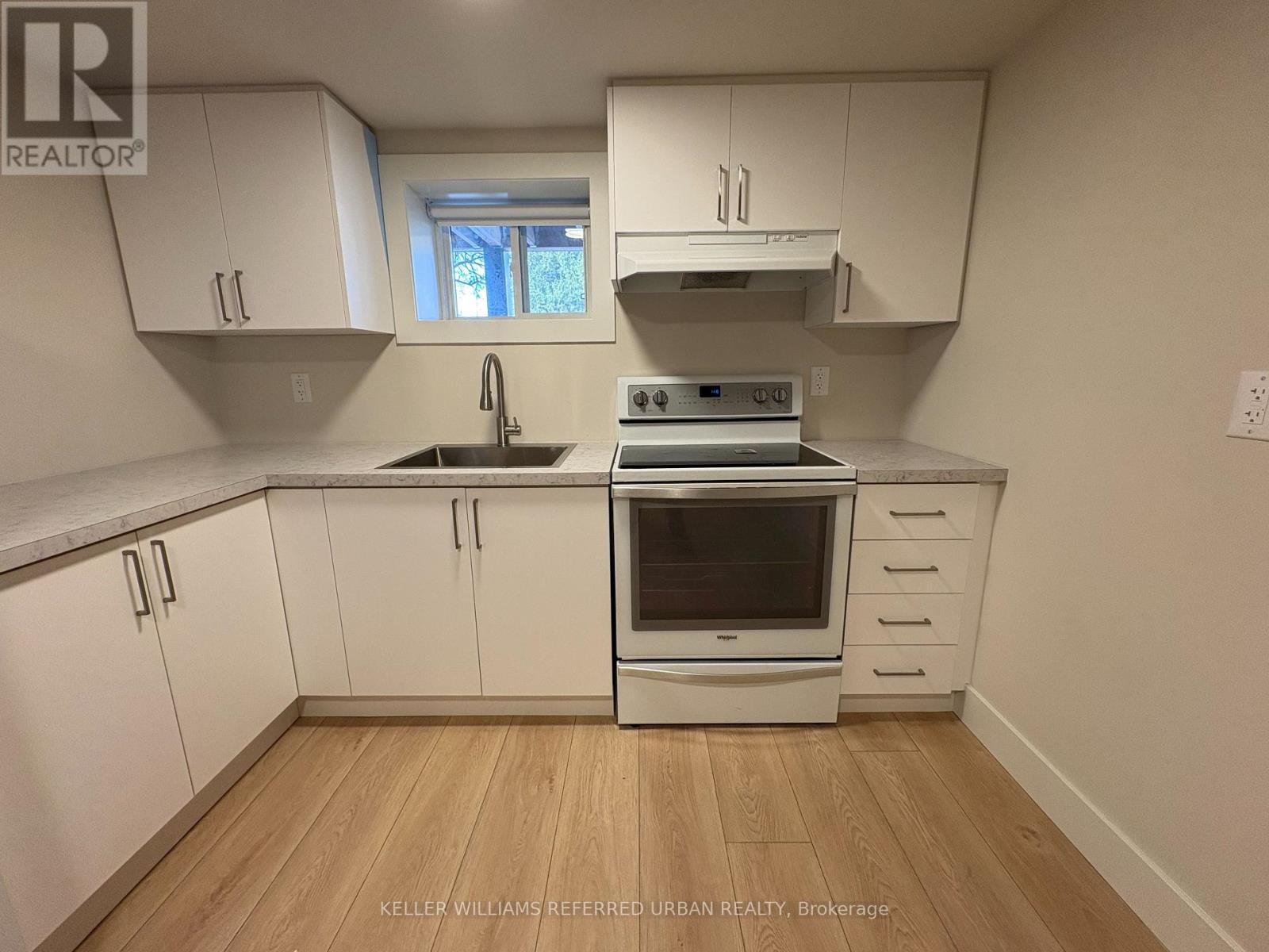 A kitchen with white cabinets and a stove top oven.