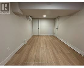 A spacious room with wooden flooring and white walls.