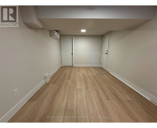 A spacious room with wooden flooring and white walls.