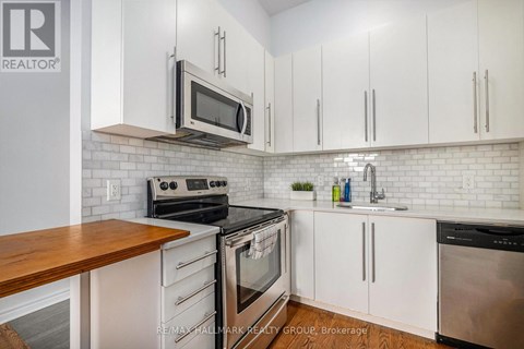 A kitchen with white cabinets and a wooden counter top.