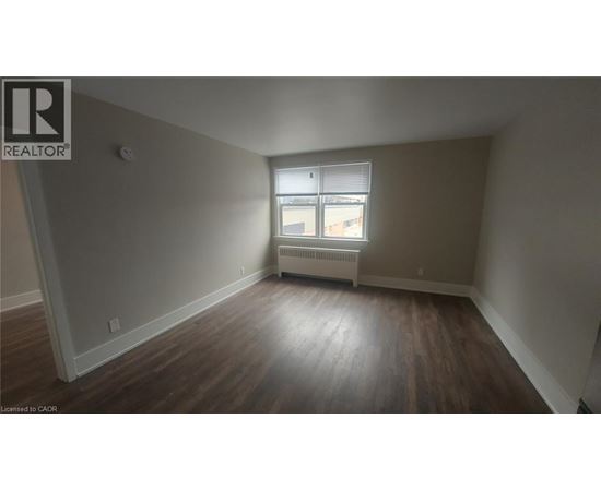 A room with wooden floors and a window with blinds.