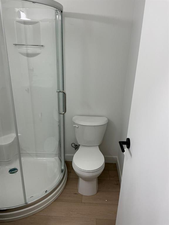 A white toilet sits next to a glass shower stall.