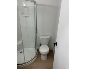 A white toilet sits next to a glass shower stall.