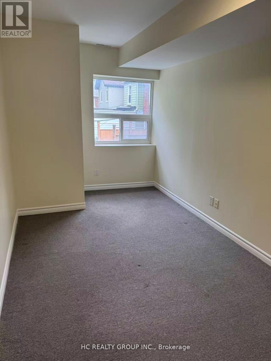 A room with a carpeted floor and a window showing a building outside.