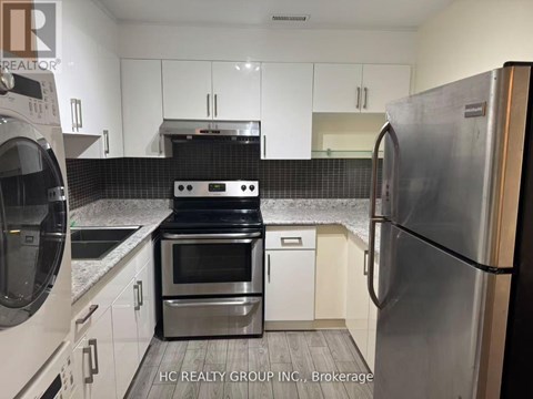 A kitchen with white cabinets and a black stove top oven.