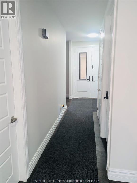 A hallway with a carpeted floor and white walls.