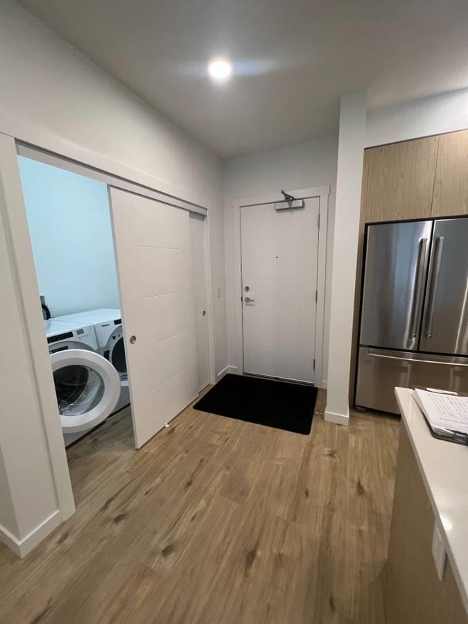 A small, clean, and well-lit kitchen with wood flooring and a refrigerator.