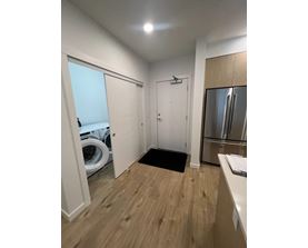 A small, clean, and well-lit kitchen with wood flooring and a refrigerator.