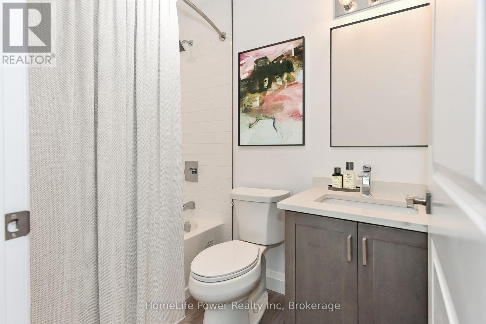 A bathroom with a toilet, sink, and a painting on the wall.