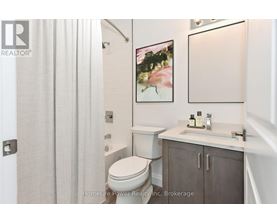 A bathroom with a toilet, sink, and a painting on the wall.