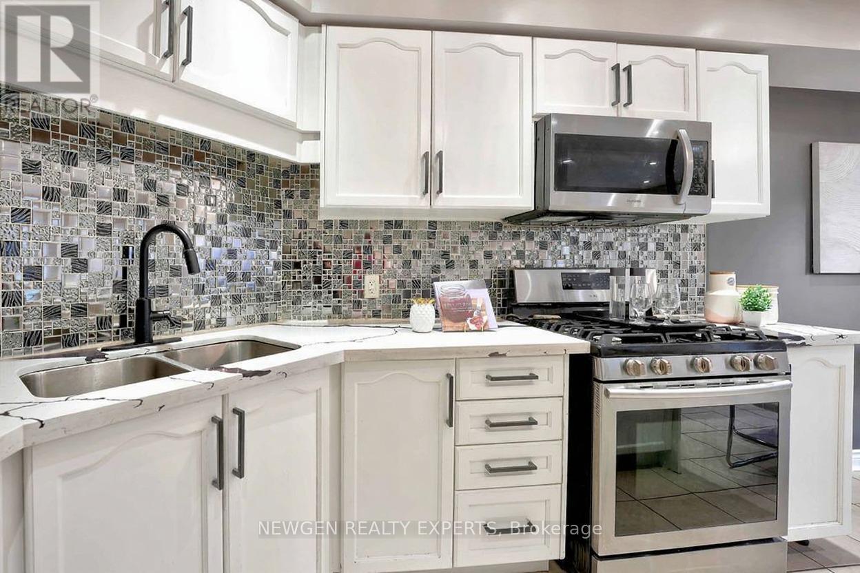 A kitchen with white cabinets and a black faucet.