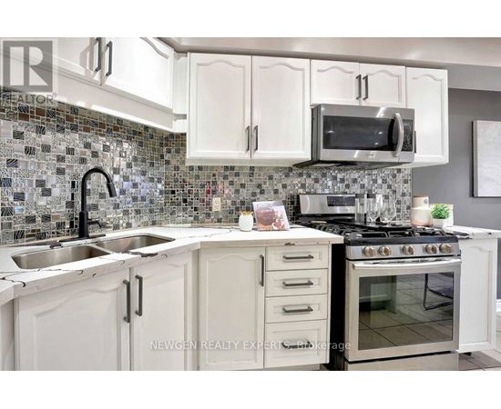 A kitchen with white cabinets and a black faucet.