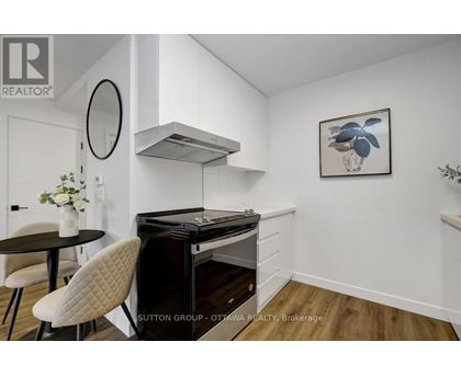 A modern kitchen with a black stove top oven and a round mirror above it.