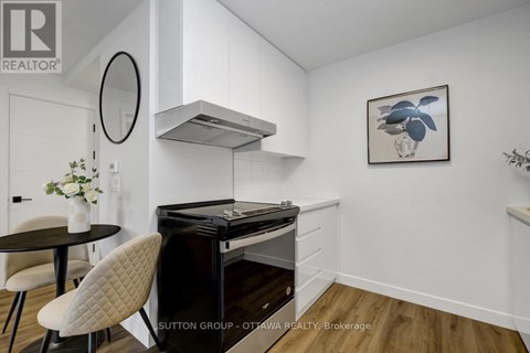 A modern kitchen with a black stove top oven and a round mirror above it.