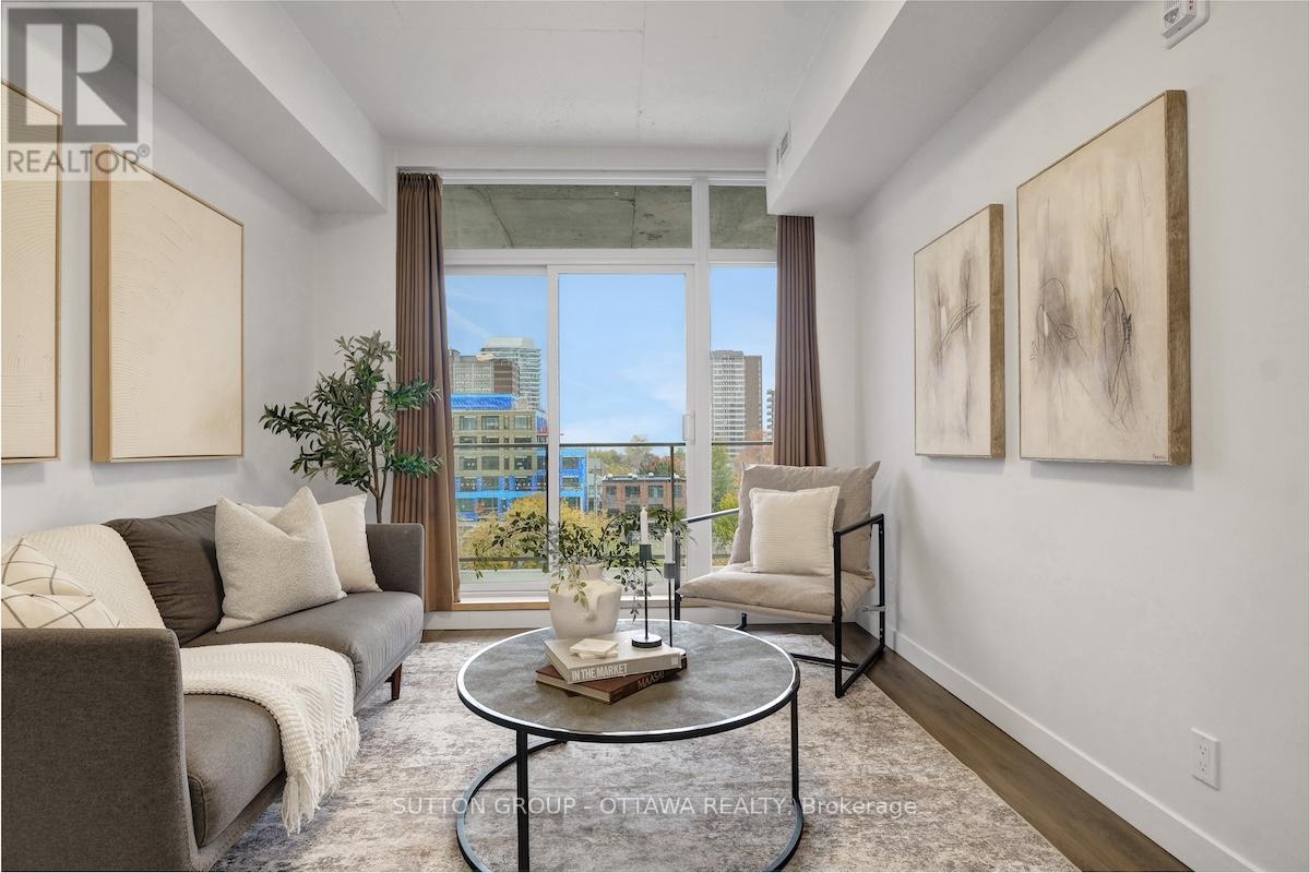 A living room with a grey couch, a coffee table, and two paintings on the wall.