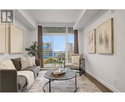 A living room with a grey couch, a coffee table, and two paintings on the wall.