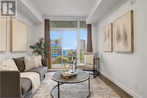 A living room with a grey couch, a coffee table, and two paintings on the wall.