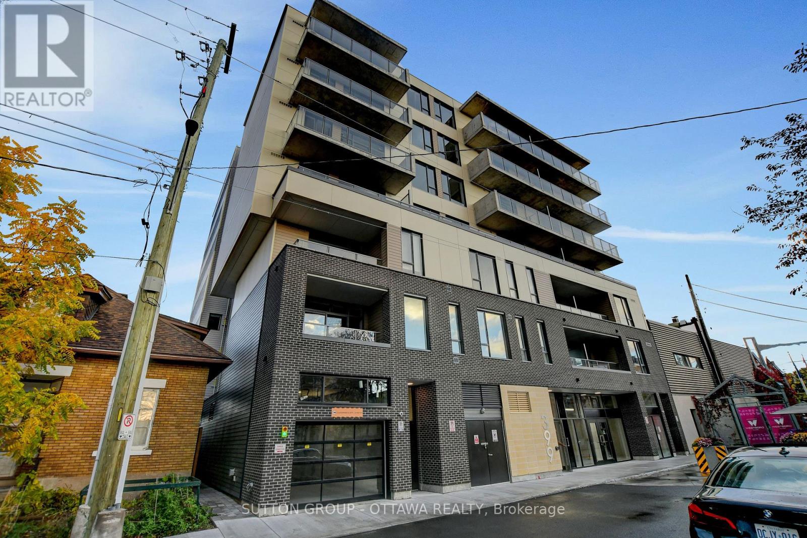 A modern apartment building with a glass facade and a brick chimney.