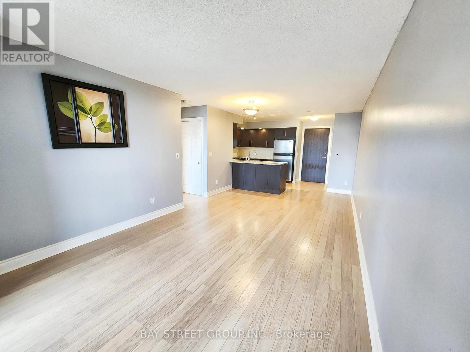 A spacious room with wooden flooring and a framed picture on the wall.