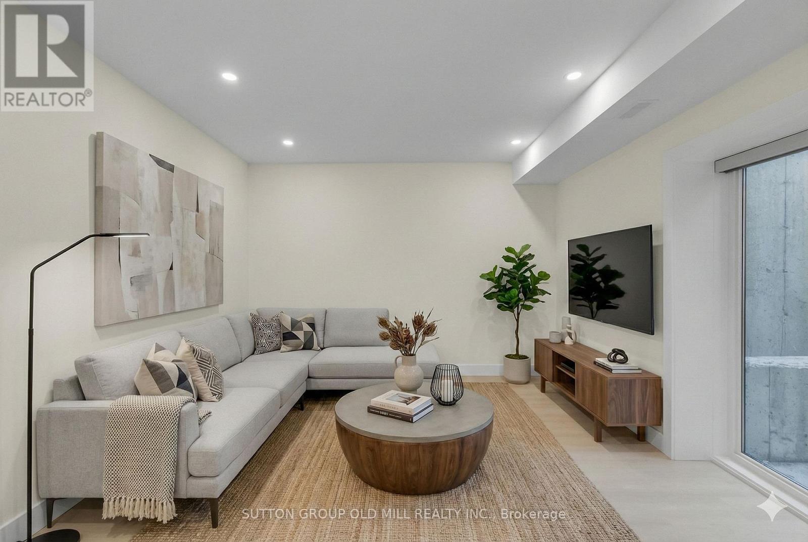 A living room with a grey couch, a coffee table, and a flat screen TV mounted on the wall.
