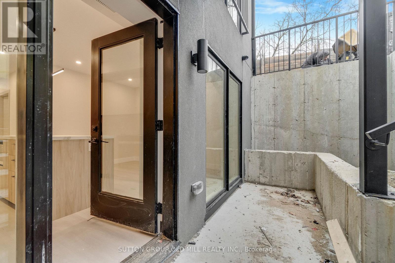 A modern house entrance with a glass door and a concrete wall.