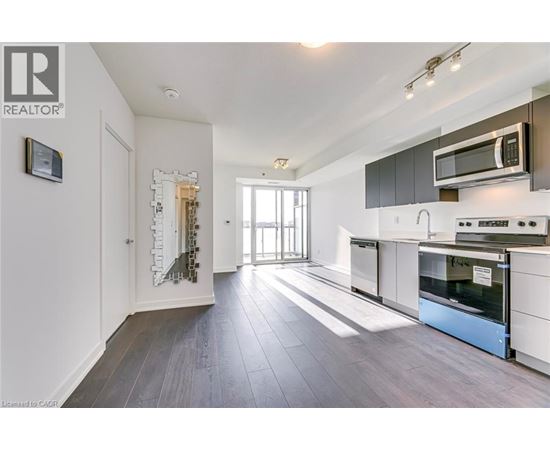 A modern kitchen with white cabinets and a wooden floor.