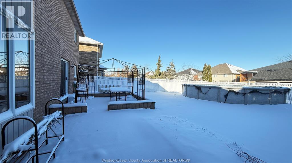 A snow-covered yard with a building and a fence in the background.