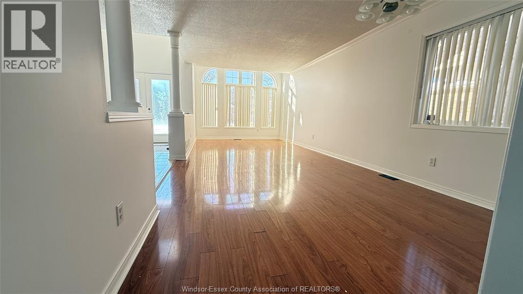 A spacious room with wooden floors and a large window.