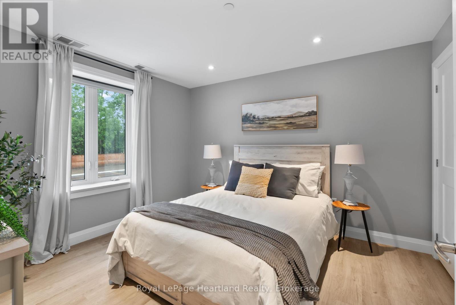 A bedroom with a large bed and a painting on the wall.