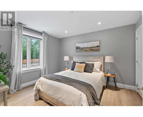 A bedroom with a large bed and a painting on the wall.