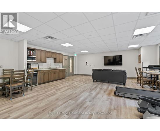 A spacious room with wooden flooring and furniture including a couch, chairs, and a dining table.