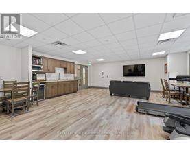 A spacious room with wooden flooring and furniture including a couch, chairs, and a dining table.