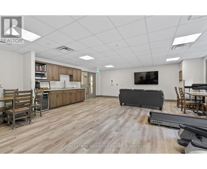 A spacious room with wooden flooring and furniture including a couch, chairs, and a dining table.