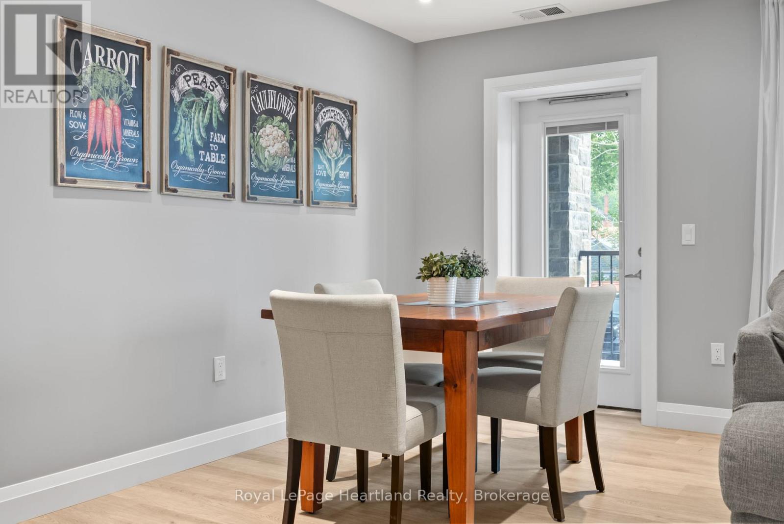 A dining room with a table and chairs and pictures of vegetables on the wall.