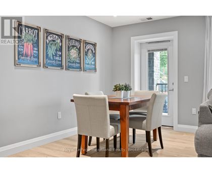 A dining room with a table and chairs and pictures of vegetables on the wall.