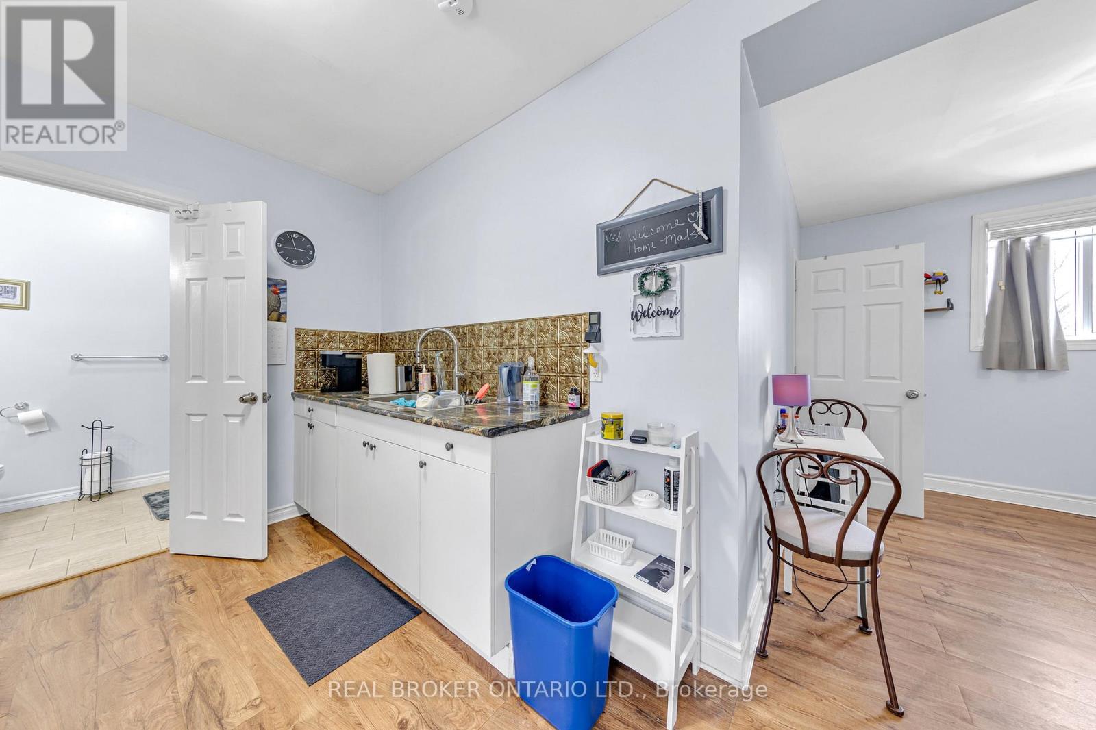 A kitchen with white cabinets and a blue trash can.