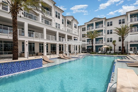 A large swimming pool in front of a white apartment building.