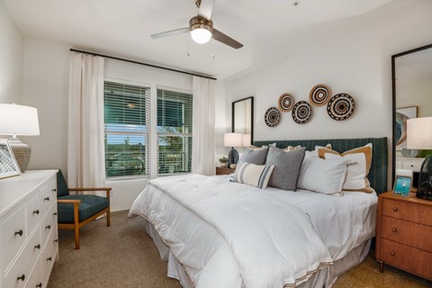 A bedroom with a large bed, a dresser, and a ceiling fan.