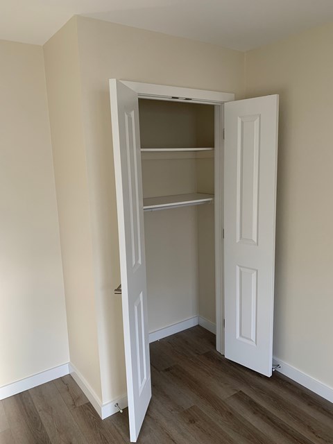 A white door is open to a room with a shelving unit.