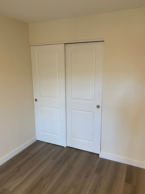 A room with a white door and a brown floor.