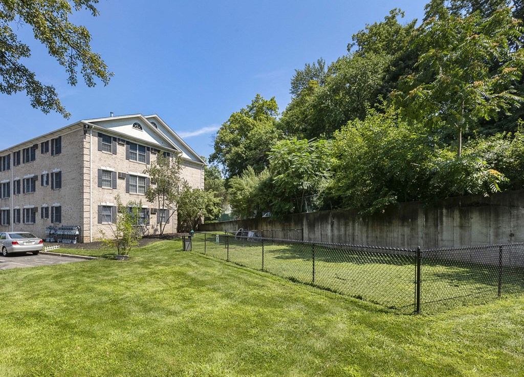 the yard of an apartment building with a chain link fence and a grassy yard