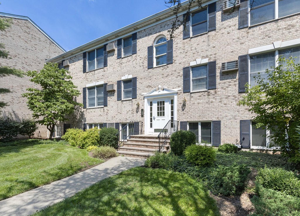 the front of a brick apartment building with a sidewalk in front of it