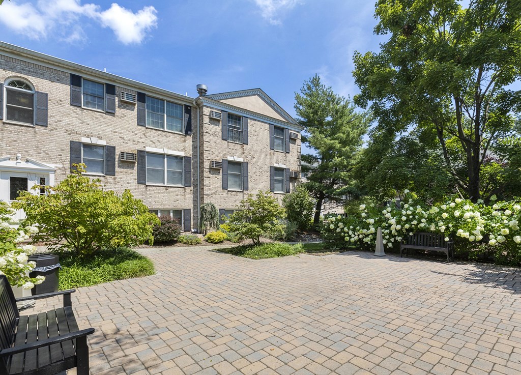 a brick apartment building with a brick driveway and a bench