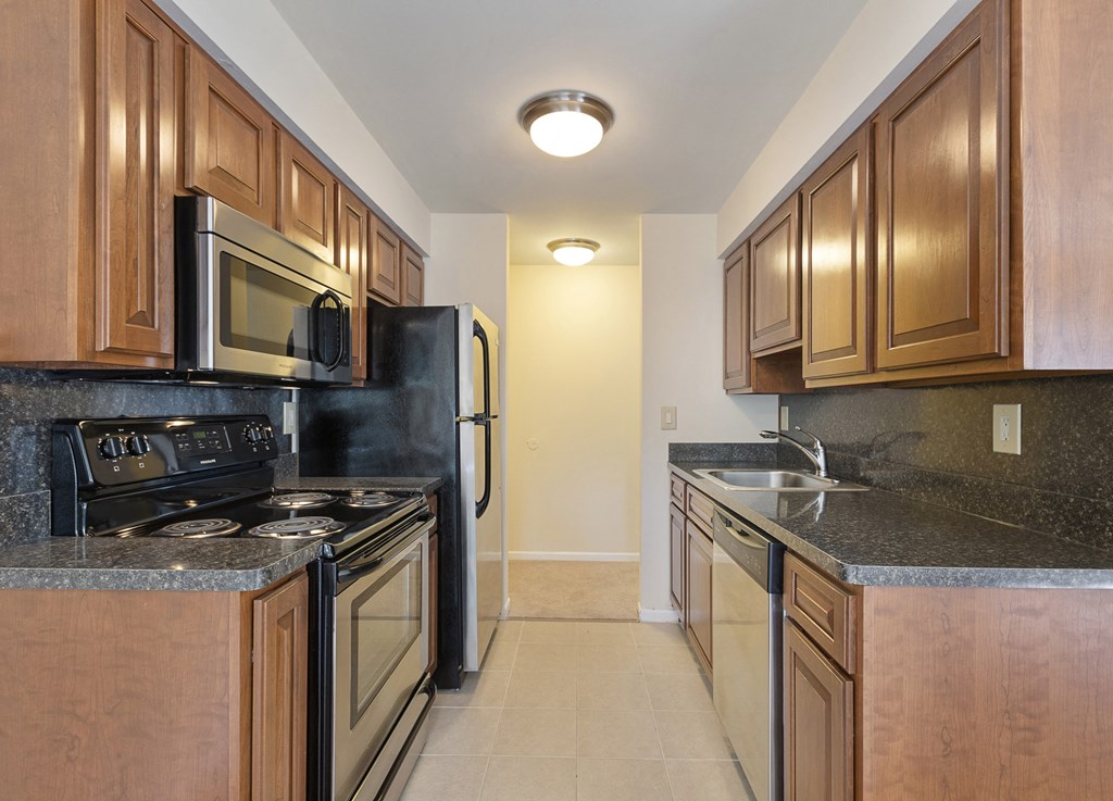 a kitchen with wood cabinets and black appliances and granite counter tops